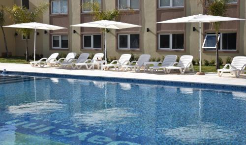 a group of chairs and umbrellas next to a swimming pool at Days Inn Zarate in Zárate