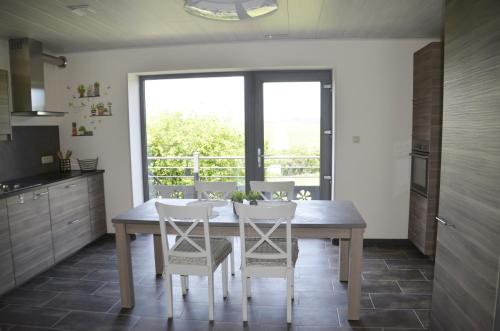 cocina con mesa de madera y sillas blancas en Gîtes Paille-Foin, en Cerfontaine