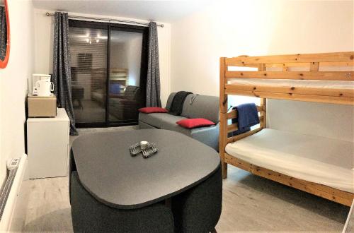 ein kleines Zimmer mit einem Tisch und einem Etagenbett in der Unterkunft travelski home classic - Résidence Soyouz in Le Corbier