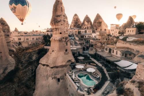 a group of hot air balloons flying over a city at Aza Cave Cappadocia in Göreme