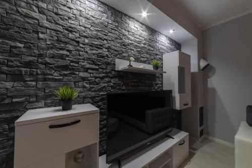 a living room with a tv and a brick wall at Villa Ban in Trogir