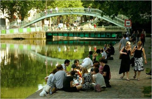Un groupe de personnes assises à côté d'une masse d'eau dans l'établissement Charmante studette Paris Canal Saint Martin, à Paris