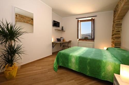 a bedroom with a green bed and a table at Petra Holiday Home in Pietrapertosa