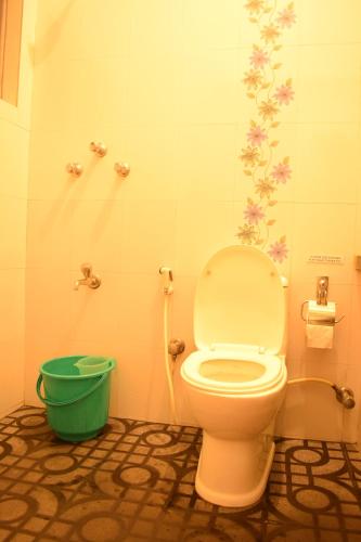 a bathroom with a toilet and a green bucket at BE ANIMAL Hostel in Bangalore
