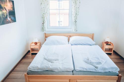 a bedroom with a bed with white sheets and a window at Penzion La Piccolina in Nový Bor