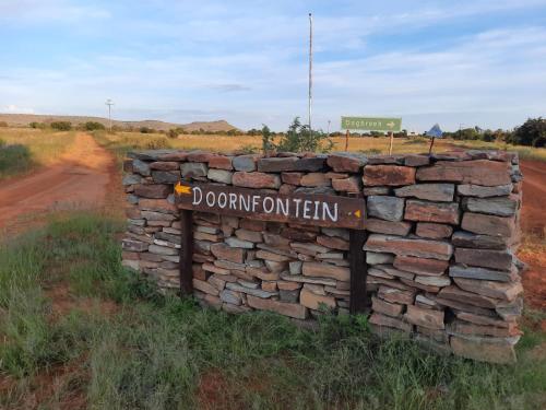 a stone wall with a sign in the middle of a road at Doornfontein Guest Farm in Cradock