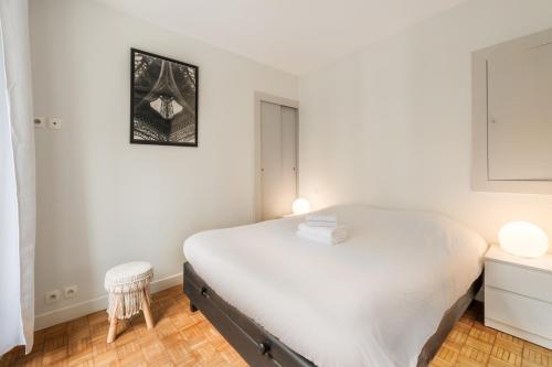 a white bedroom with a bed and a stool at Apart of Paris - Chatelet - Rue de Rivoli in Paris