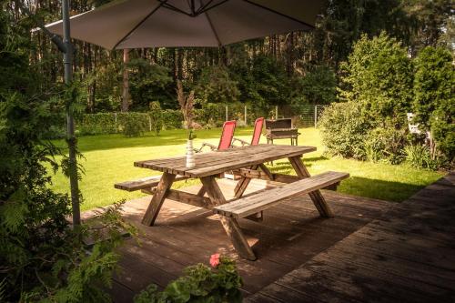 a wooden picnic table with two chairs and an umbrella at Lauku iela 25 in Jūrmala