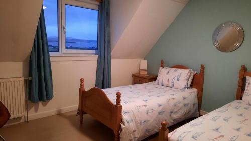 a bedroom with two beds and a window at Seascape Cottage in Knock