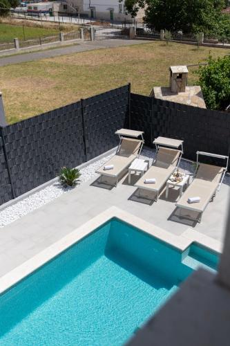 a group of lounge chairs and a swimming pool at Villa Ban in Trogir