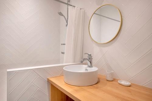 une salle de bain blanche avec un lavabo et un miroir dans l'établissement À 400m de la plage, appartement pour 8, à La Baule