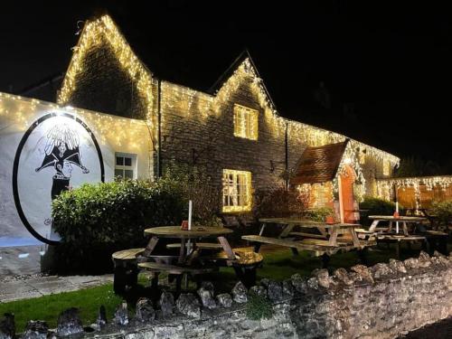 a group of picnic tables in front of a building with lights at The Prince of Waterloo - Boutique Guest Rooms in Winford