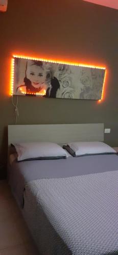 ヴェローナにあるBorgo Roma vic Fieraのベッドルーム1室(壁に照明付きのベッド1台付)