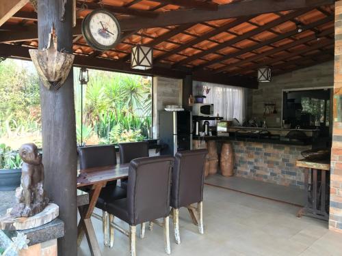 a dining room with a table and chairs and a clock at Estância das Angolas - Inhotim in Brumadinho