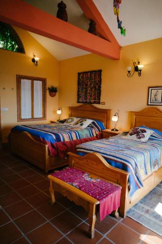 a bedroom with two beds and a bench in a room at Hotel La Casa del Mundo in Jaibalito