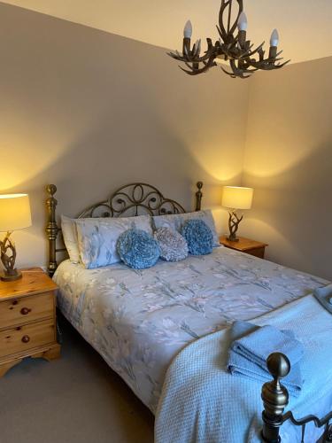 a bedroom with a bed with blue sheets and two lamps at Spaniel Cottage with views of Ham hill, Stoke sub Hamdon in Martock