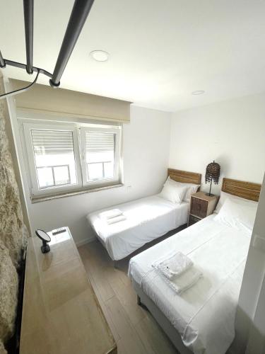 two beds in a room with two windows at Portoo Blue Apartments - Douro in Vila Nova de Gaia