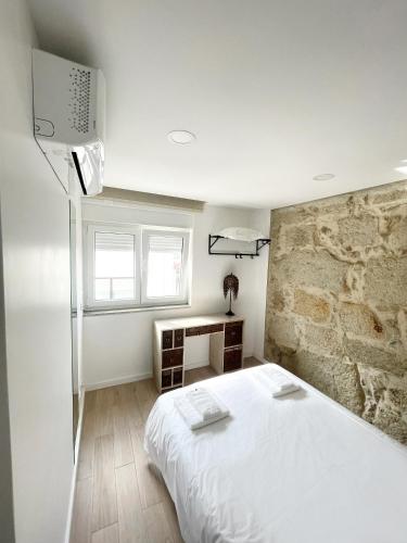 a bedroom with a white bed and a stone wall at Portoo Blue Apartments - Douro in Vila Nova de Gaia