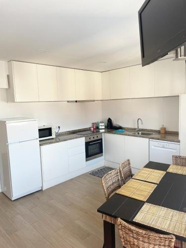 a kitchen with white cabinets and a table with chairs at Portoo Blue Apartments - Douro in Vila Nova de Gaia