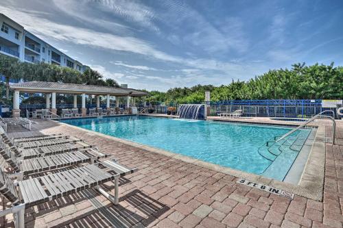 a large swimming pool with chairs and a building at Walk to Ocean Condo with Pool in New Smyrna Beach in New Smyrna Beach