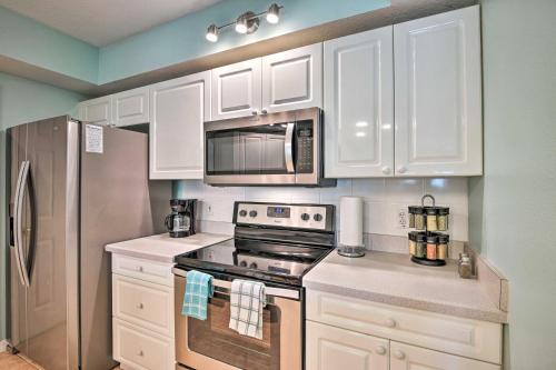 a kitchen with white cabinets and a stove and a refrigerator at Walk to Ocean Condo with Pool in New Smyrna Beach in New Smyrna Beach