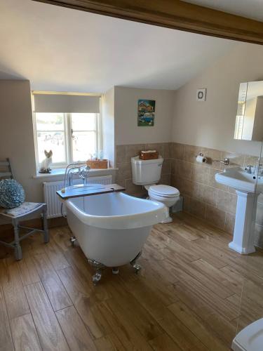 a bathroom with a tub and a toilet and a sink at Spaniel Cottage with views of Ham hill, Stoke sub Hamdon in Martock