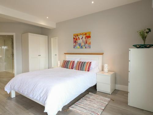 a bedroom with a white bed and a white cabinet at Slitting Mill Annex in Rugeley