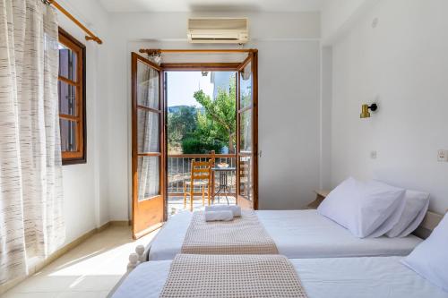 1 dormitorio con 2 camas y balcón en Skopelos Evergreen Apartments, en Stafylos