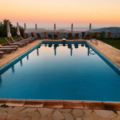 a large swimming pool with chairs and umbrellas at Domaine du Bois d'Amont in Cabris