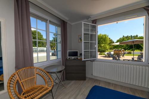 ein Wohnzimmer mit einem großen Fenster, einem Schreibtisch und einem Stuhl in der Unterkunft Résidence Romaric in Jard-sur-Mer