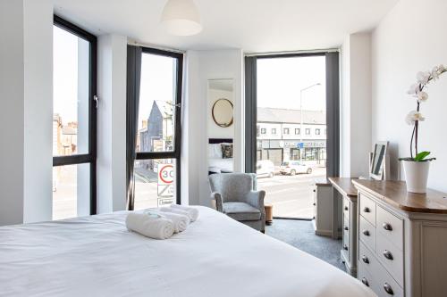 a bedroom with a bed and a desk and windows at Luxury 2BR apartments by Luxus Fully Equipped Kitchen, Ormeau Park in Belfast