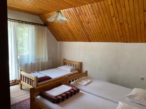 two beds in a room with a wooden ceiling at Apartments Vuković in Žabljak