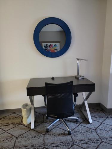 a desk with a chair and a mirror on the wall at Wingate by Wyndham Greenville Airport in Greenville