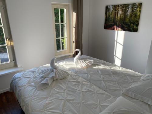 a white bed in a bedroom with two swans on it at Aaltje’s Hoeve in Ermelo