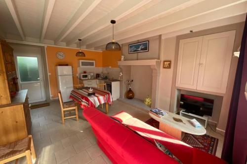 a living room with a red couch and a kitchen at Gîte en Cotentin in Étienville