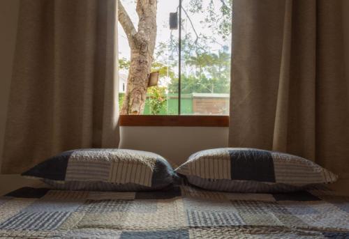 a bedroom with two pillows on a bed with a window at Hospedaria Oitis in Búzios