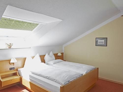 a bedroom with a white bed with a skylight at Gästehaus Bauer am Golfplatz in Prien am Chiemsee