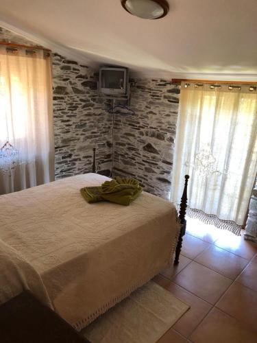 a bedroom with a bed and a tv on a stone wall at Cantinho Casal do Rei in Seia