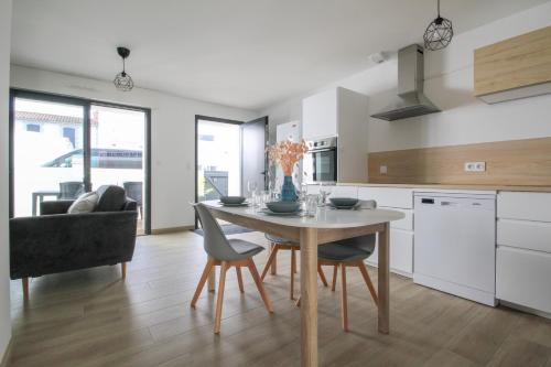 Una cocina con una mesa y sillas en una habitación. en Appartement neuf, 150m de la grande plage, parking, proche commerces, en Saint Gilles Croix de vie
