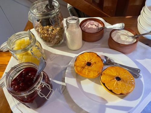a table with a white plate of fruit and jams at Arrowtown House Boutique Hotel in Arrowtown