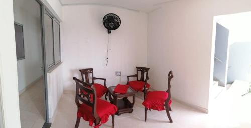 uma sala de jantar com cadeiras vermelhas e um relógio na parede em Hotel Gueicer Cucuta em Cúcuta