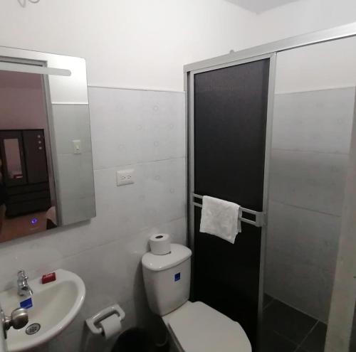 uma casa de banho com um WC, um lavatório e um espelho. em Hotel Gueicer Cucuta em Cúcuta