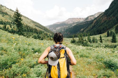 a woman with a backpack walking through a field at High Country Motor Lodge - Near NAU and Downtown in Flagstaff