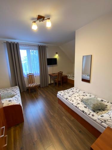 a hotel room with two beds and a table at Agroturystyka Pod Jodłami in Kołaki Wietrzychowo