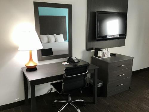 a hotel room with a desk with a bed and a mirror at Howard Johnson by Wyndham Spokane in Spokane