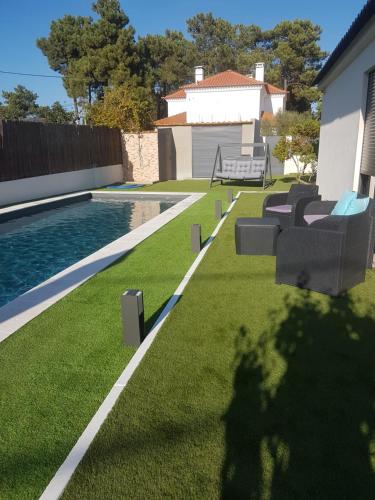 a backyard with a swimming pool and lawnitures at Marisol Sunset in Charneca