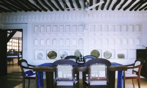 een tafel met stoelen en borden aan een muur bij Shela Bahari in Shela