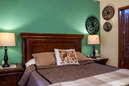 a bedroom with a bed with green walls and two lamps at Casa Maricela B&B in San Miguel de Allende