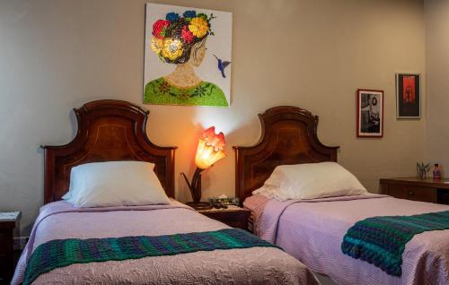 a bedroom with two beds and a painting on the wall at Casa Maricela B&B in San Miguel de Allende
