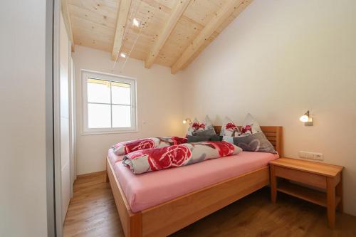 - une chambre avec un lit doté de draps rouges et une fenêtre dans l'établissement Spitzbua, à Saalfelden